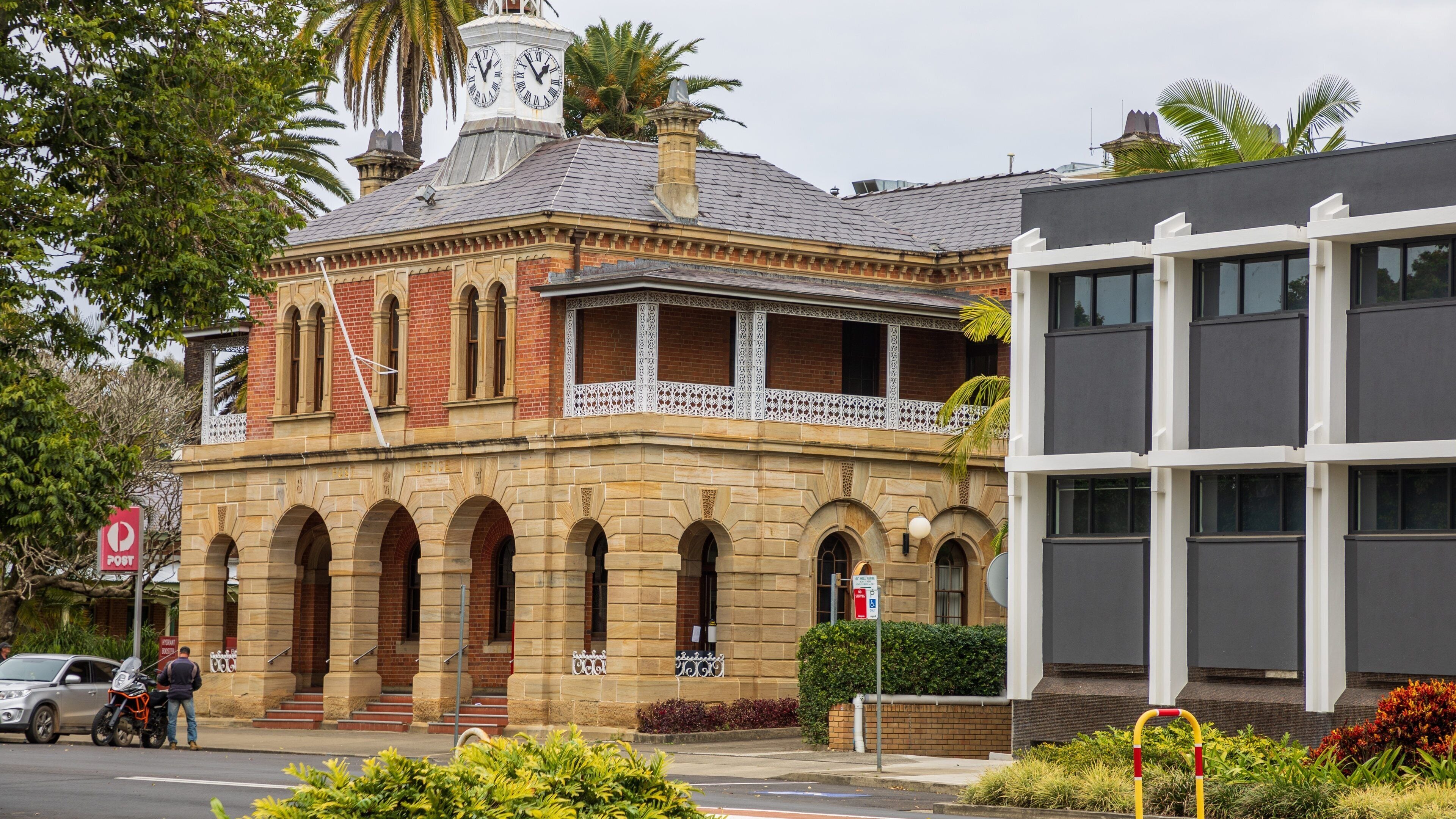 A historic building with a clock tower, arched windows, and a balcony.