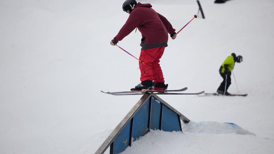 A person skiing on a rail in a snowy landscape.