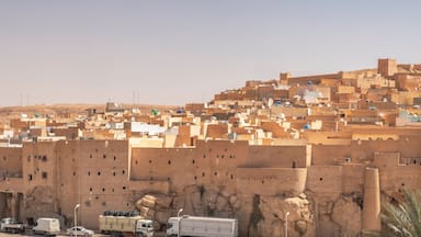 Una ciudad densamente poblada con arquitectura tradicional, que incluye una torre destacada y murallas fortificadas.