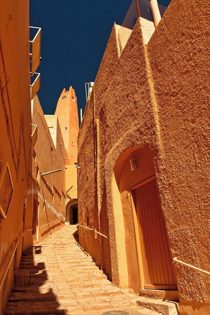 Ghardaia is the main of the five cities in the M'zab valley in Sahara, some 600 km south from Algiers and Medditeranean Sea. The cities of this pentapolis are Ghardaia (capital), Bounura, Beni Isguen (most sacred), Melika (main cemetery) and Al-Atteuf (oldest part) have walled centers (called Ksars) with a fortress-like mosque and minaret and storage in the centre on a hill surrounded by a maze of narrow streets and alleys and standartized cubical houses constructed in concentric circles aroung the mosque and hill. The place was founded by the Mozabites. These were of Berber origin and in 11th centure they were defeated by Fatimids in north and found a safe refuge far from their enemies in the canyons. Ironically the have quite soon converted to the religion of their enemies so the major population is now of the Ibadi Islam sect (another major Ibadi religion places are Oman and Zanzibar). However the isolation of the communities is still present in the defense-based architecture of ksars. The palm grove oases are surrounding the ksars using the river beds of the canyon valley. 

The picture shows the street near the main mosque in Ksar of Ghardaia. 

A UNESCO World Heritage Site since 1982.