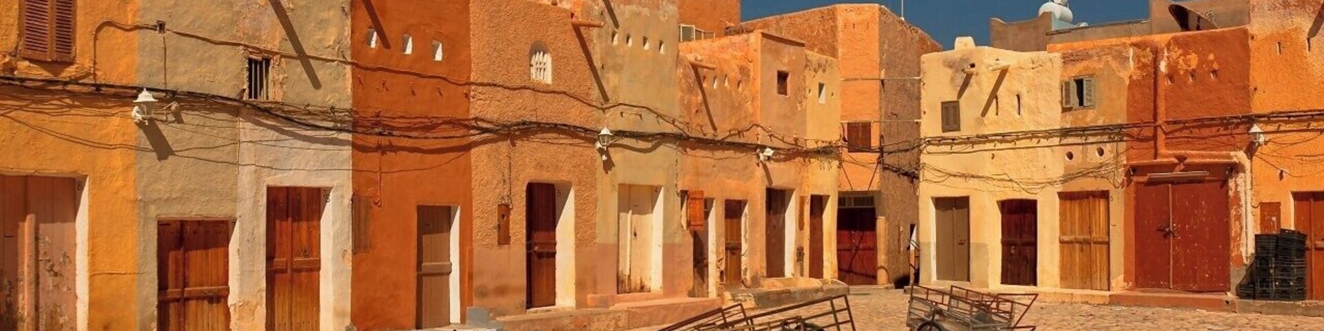 April 2011
Marché a la Criée is a market place in Beni Isguen town in M'zab valley in Algeria. Late in the afternoon it becomes the centre of the social life of Beni Isguen with the daily auction. Those who sell yell out the price of their item until someone buys it or the price is brought down.
This picture was taken during Friday prayer time, when it feels like a movie ghost town.