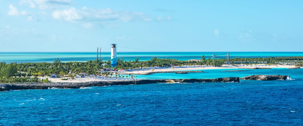 A coastal resort with a lighthouse, turquoise waters, and a sandy beach.