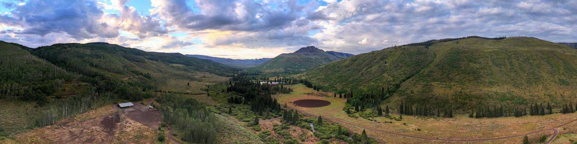 A mountainous landscape with a valley, a lake, and a road.