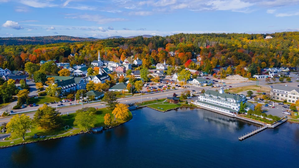A lakeside town with historic buildings, a prominent church steeple, and autumn foliage.