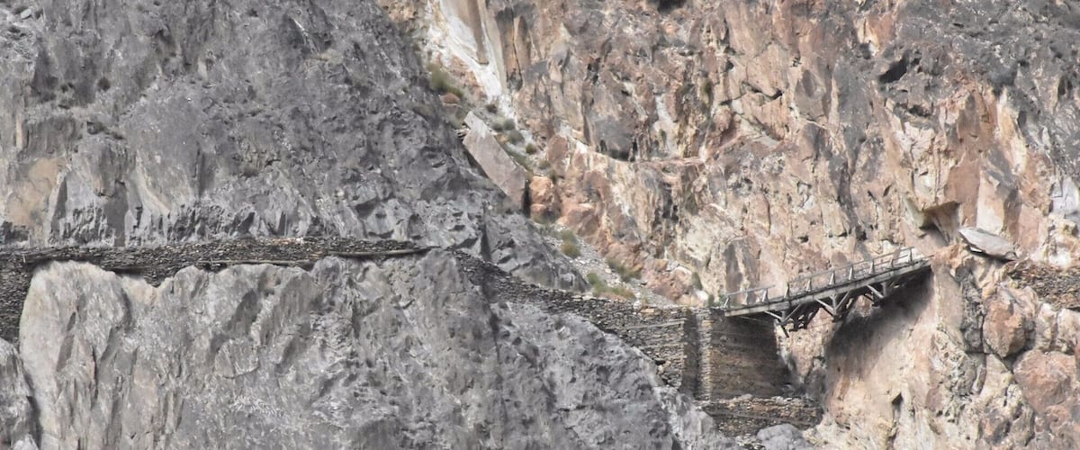 A narrow bridge spanning a deep gorge with steep rock faces on either side.