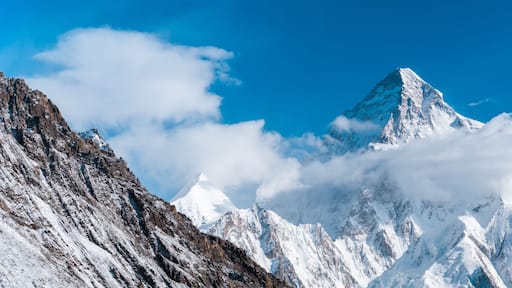 A snow-covered mountain peak with sharp ridges and a clear blue sky.