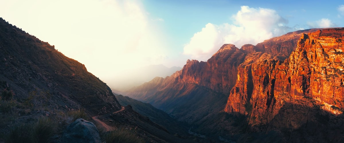 A canyon with steep, red rock walls and a winding road.