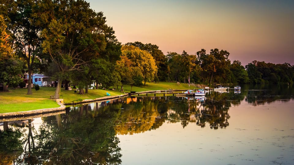 A calm lake with reflections of trees and a small dock.
