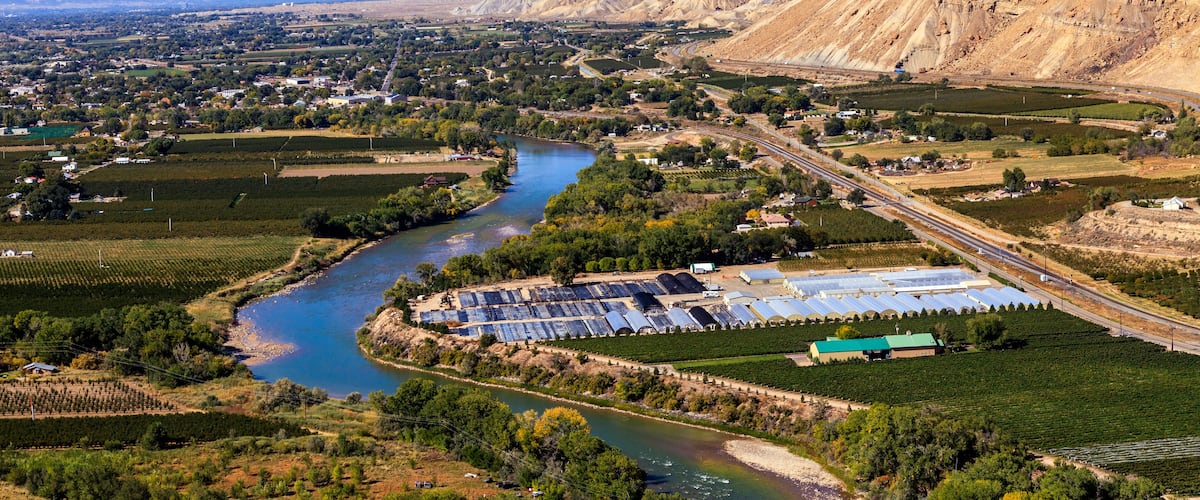 A river winding through a valley with a large solar farm and a mountain in the background.