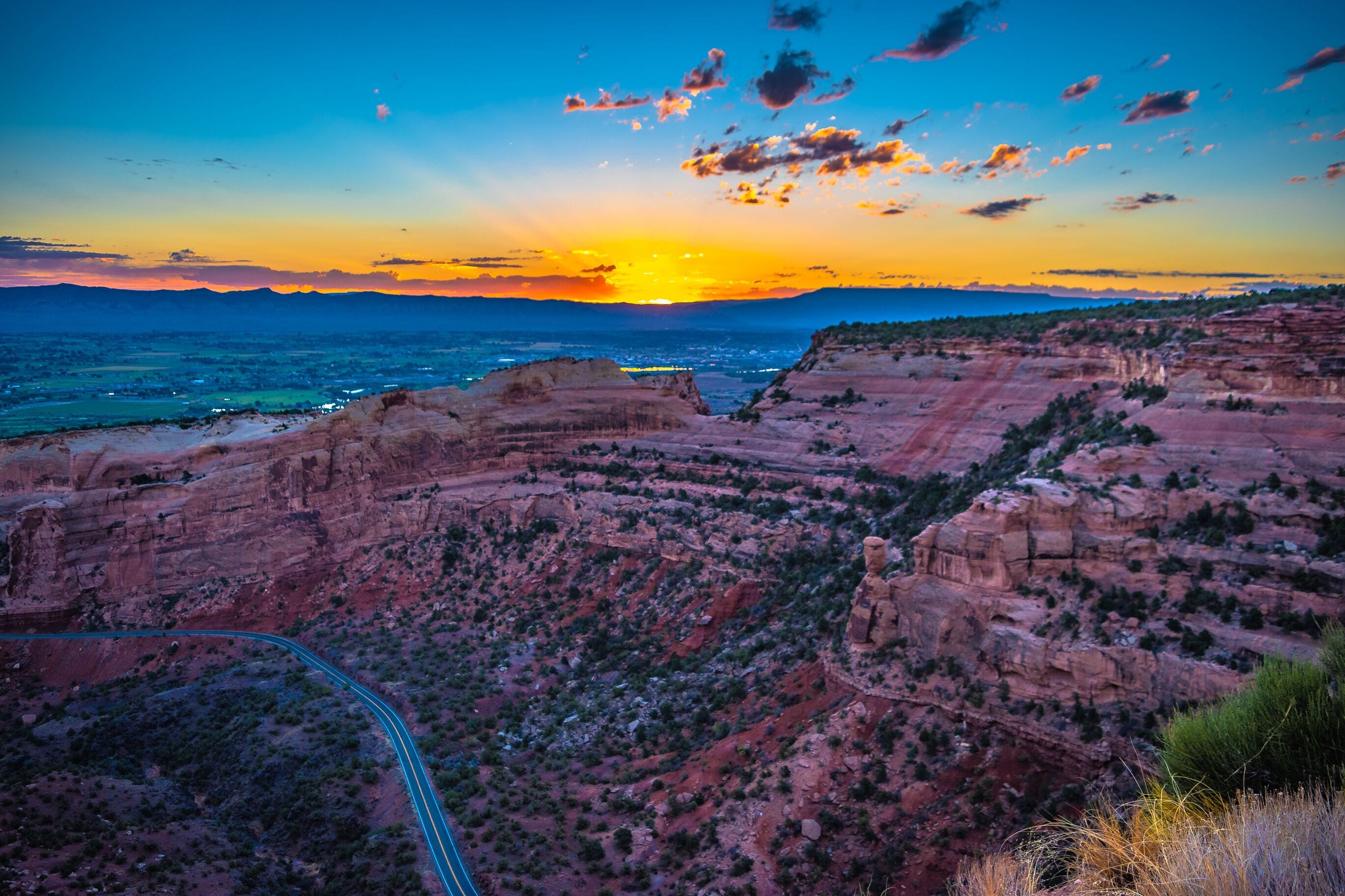 Un atardecer sobre un cañón con una carretera serpenteante.