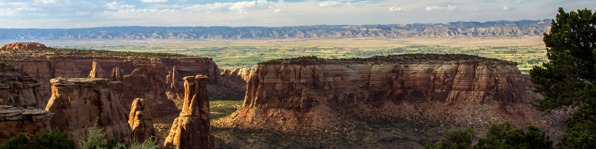A canyon with prominent rock formations and a distant mountain range.