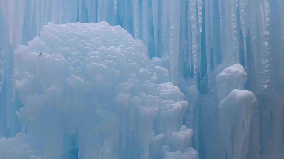 A vast icy landscape with towering ice formations and a dense cluster of snow-covered peaks.