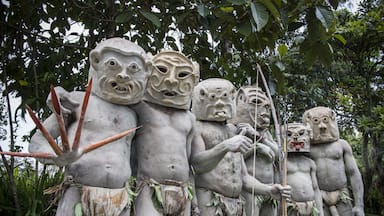 Un ensemble de statues en pierre aux traits du visage exagérés, ornées de guirlandes de feuilles.