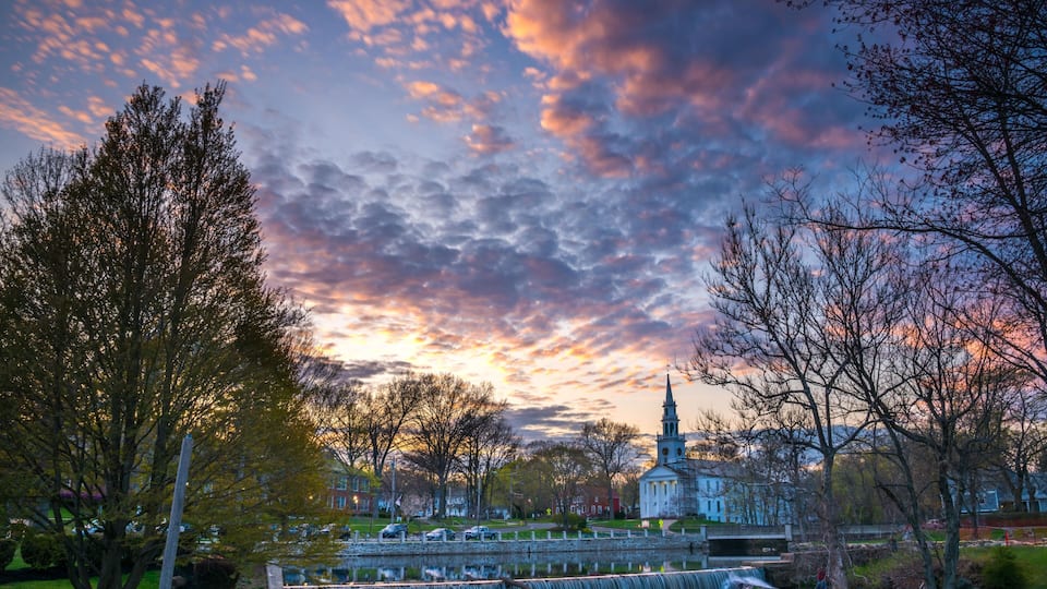A waterfall, trees, a church, and a sunset sky.