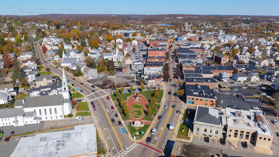 An aerial view of a town with a prominent church, a central roundabout, and surrounding residential and commercial buildings.