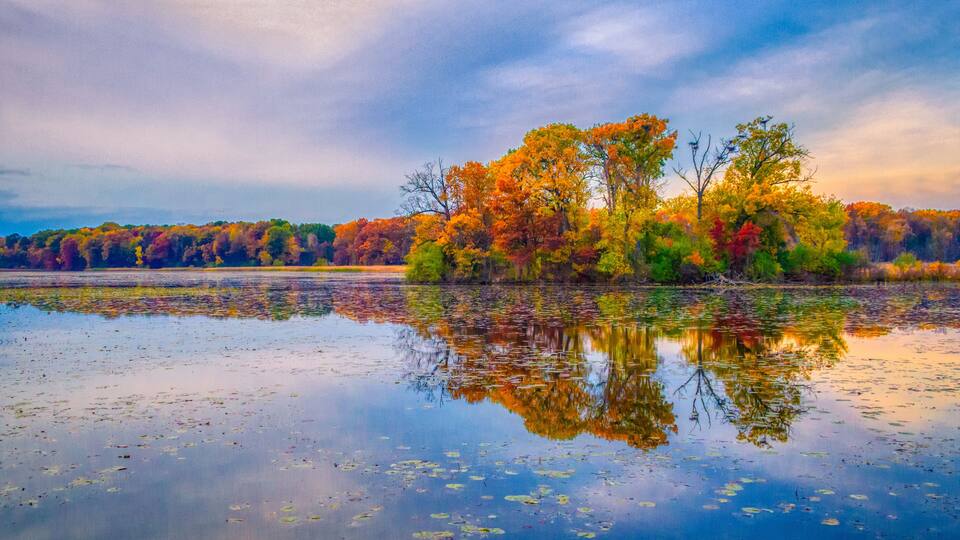 A calm lake with reflections of colorful autumn trees.