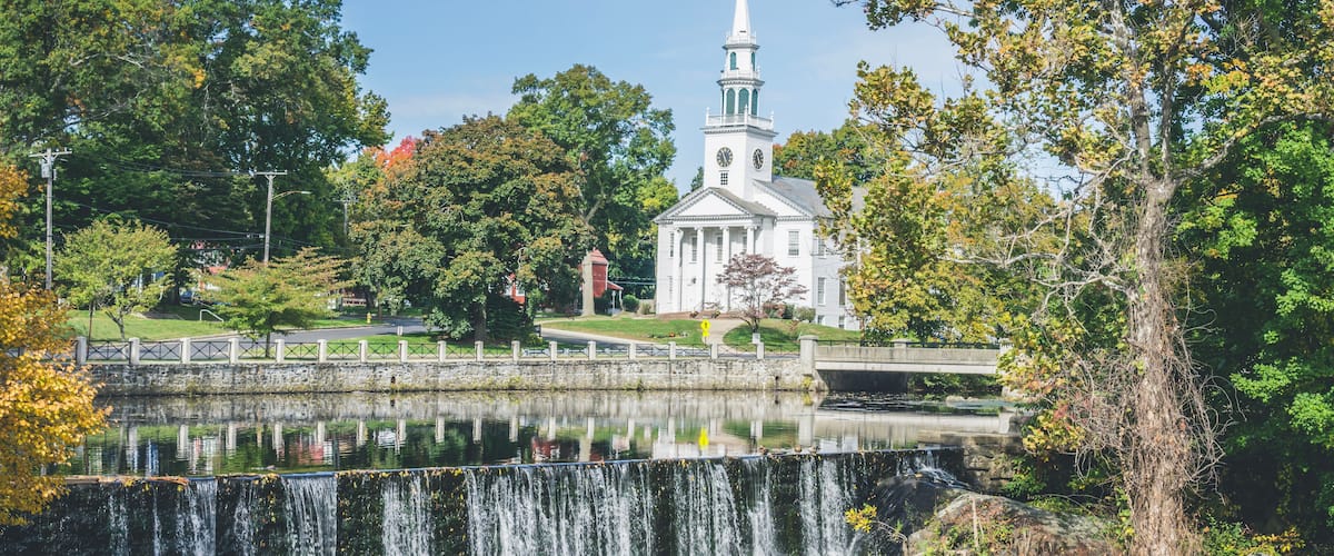 A waterfall, a church, and surrounding trees.