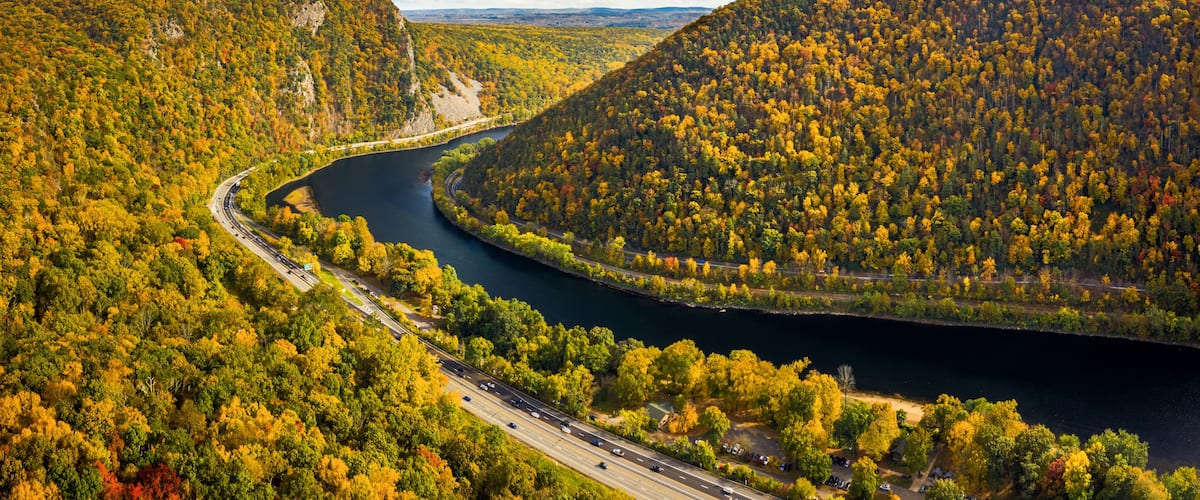 A river winding through a forested valley with a highway running alongside.