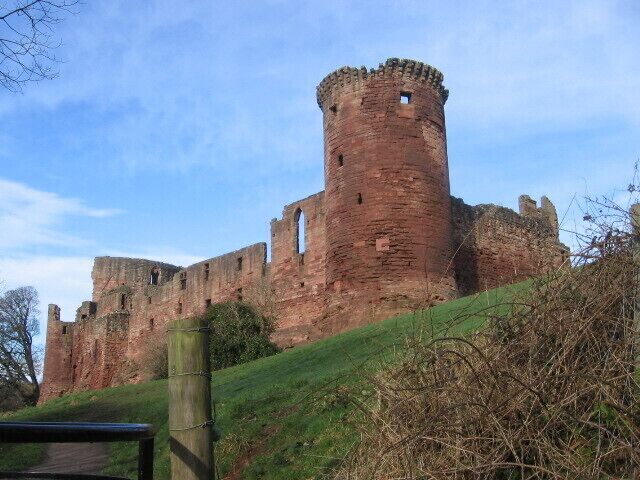 A large, historic castle with a prominent round tower and ruins.