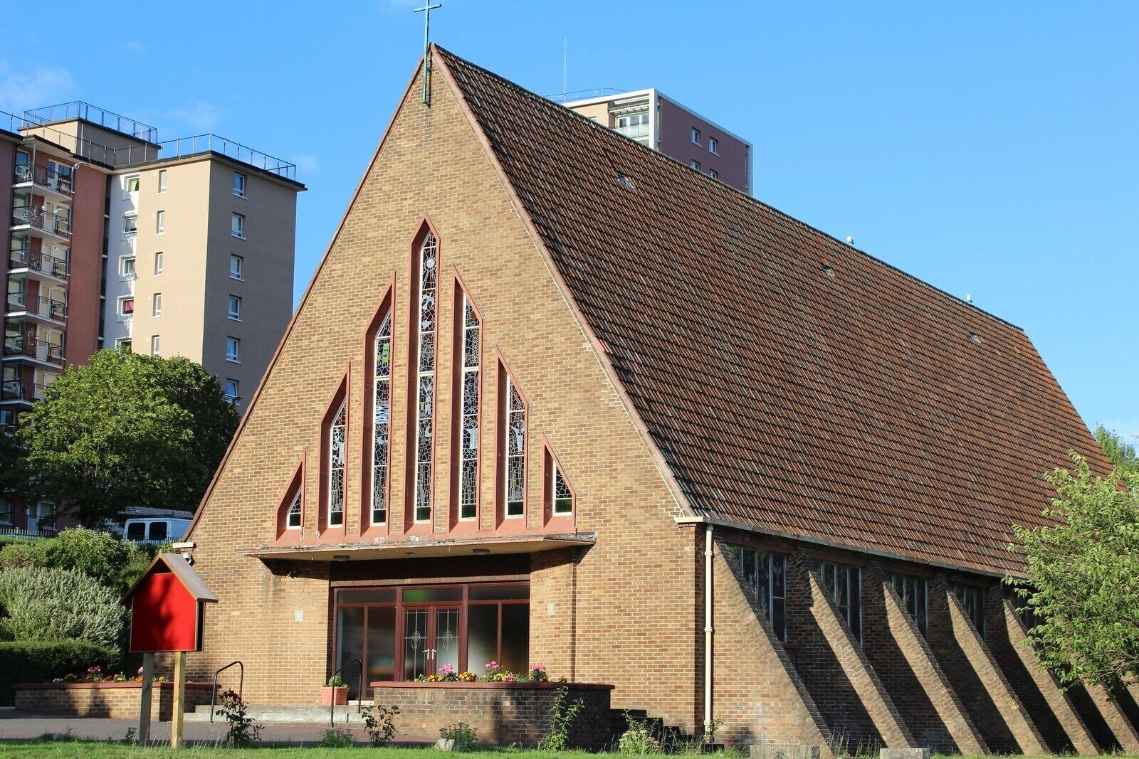 A church with a triangular roof and stained glass windows.
