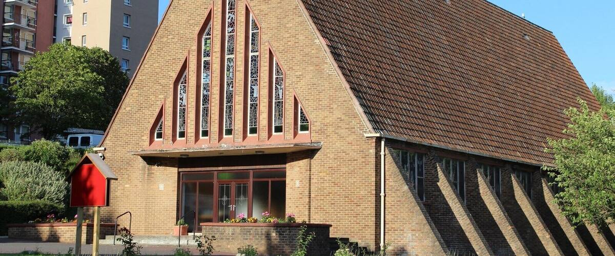 A church with a triangular roof and stained glass windows.