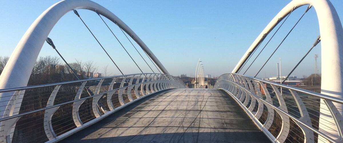 A pedestrian bridge with white arches and metal railings.