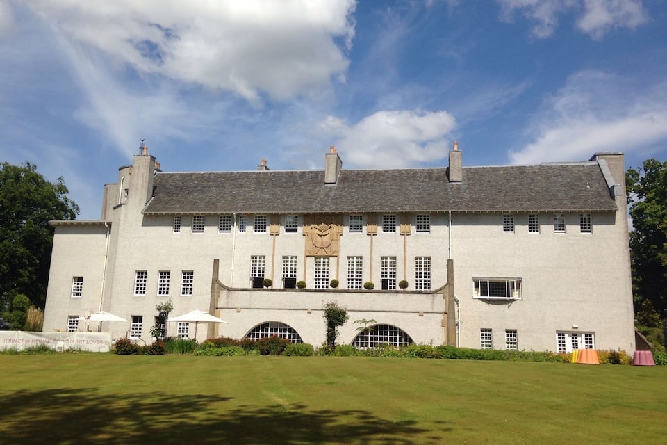 A large white building with a grey roof, multiple windows, and a central archway.