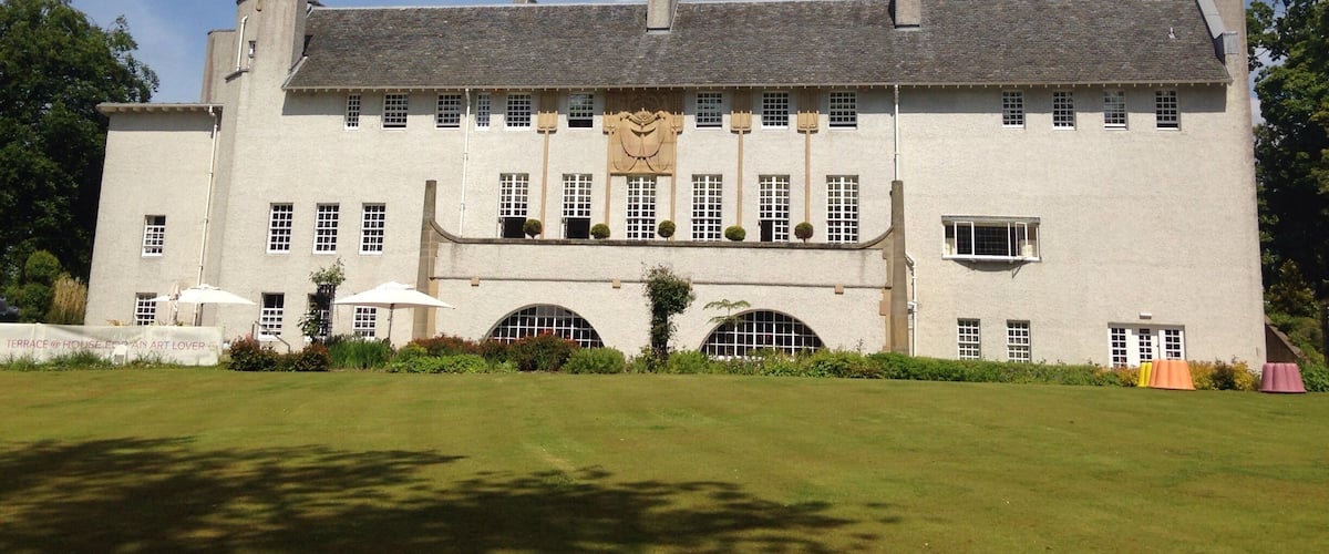 A large white building with a grey roof, multiple windows, and a central archway.