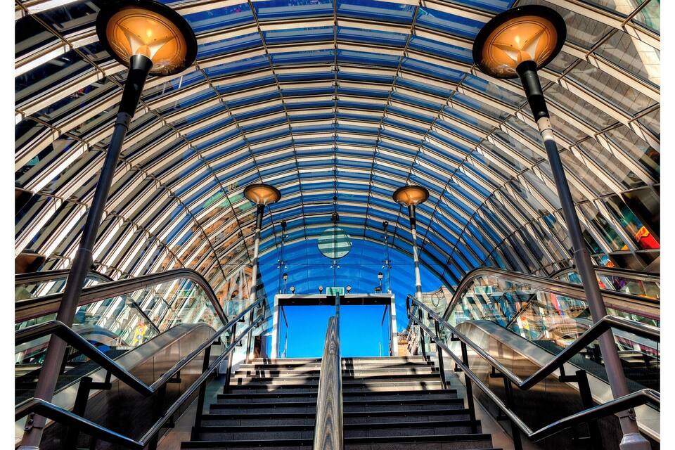 A modern architectural structure with a curved glass ceiling and metal railings.