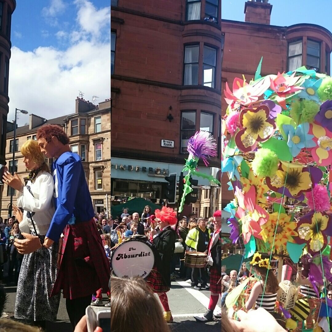 A street parade with a group of people in traditional Scottish attire, a drum band, and colorful decorations.