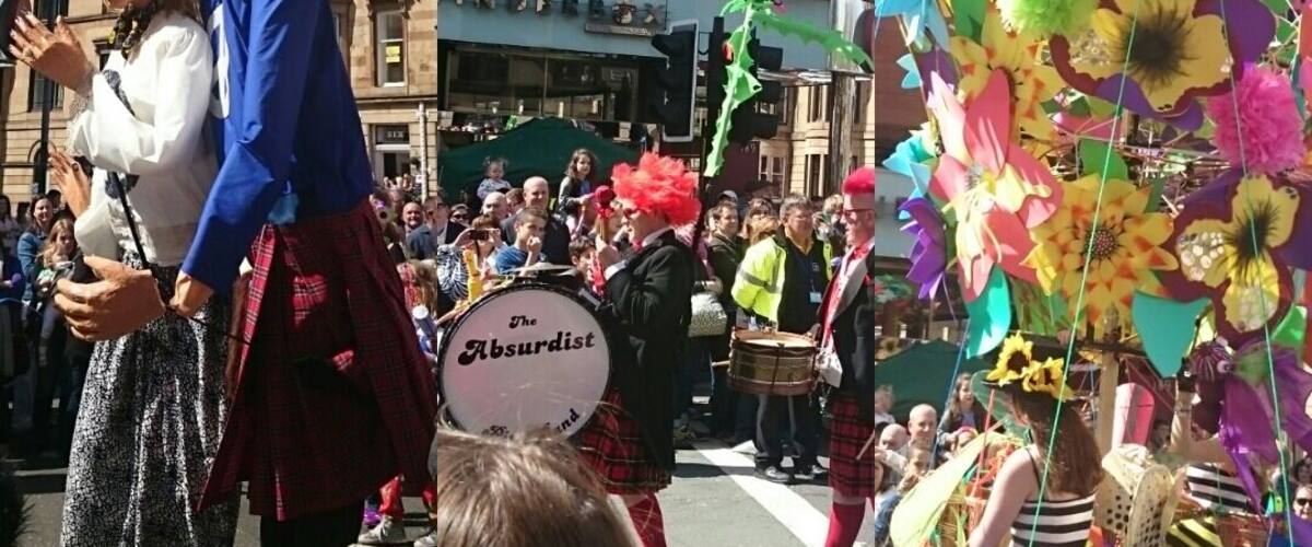 A street parade with a group of people in traditional Scottish attire, a drum band, and colorful decorations.