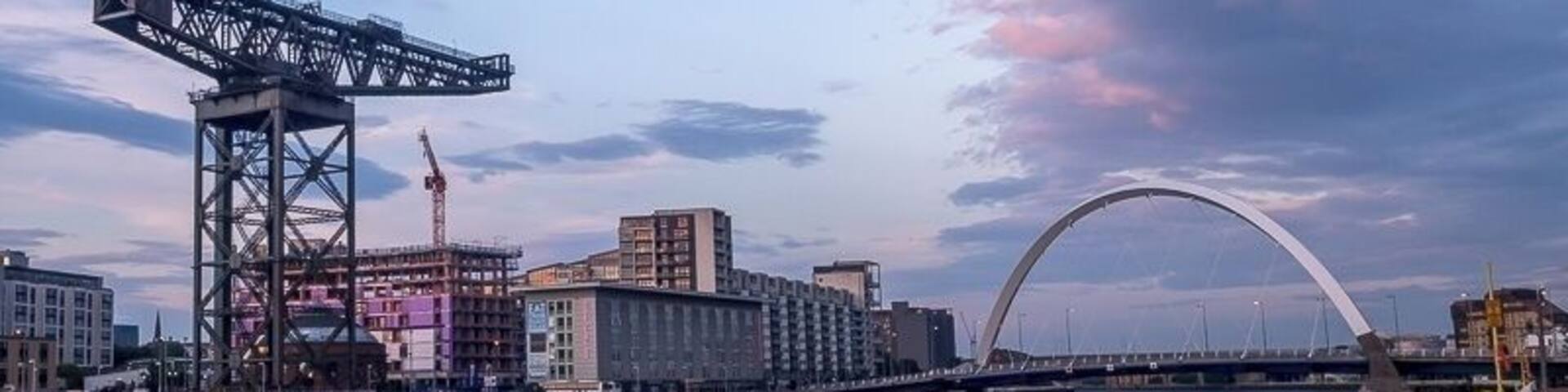 A river with a bridge, a crane, and buildings in the background.