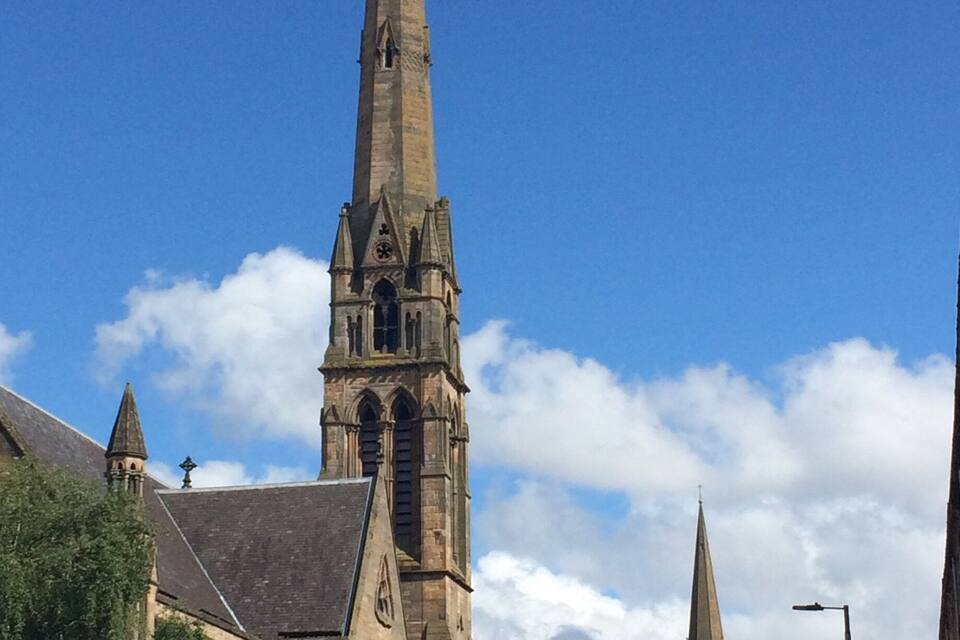 A tall church with a pointed spire and a clock tower.