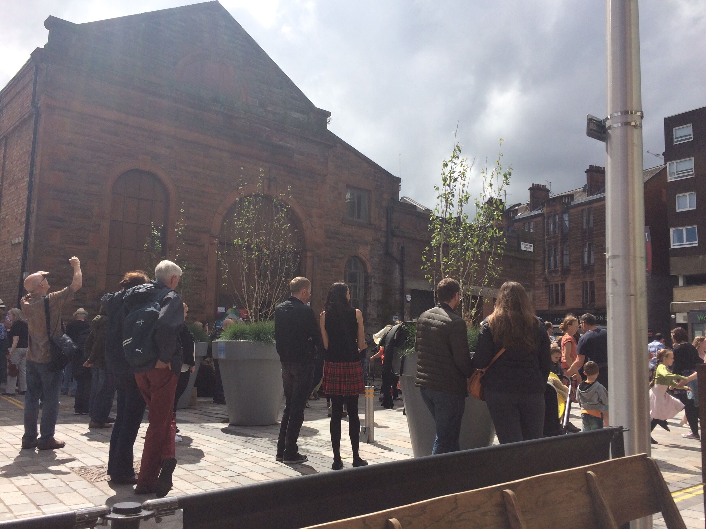 A crowded outdoor area with a historic brick building in the background.