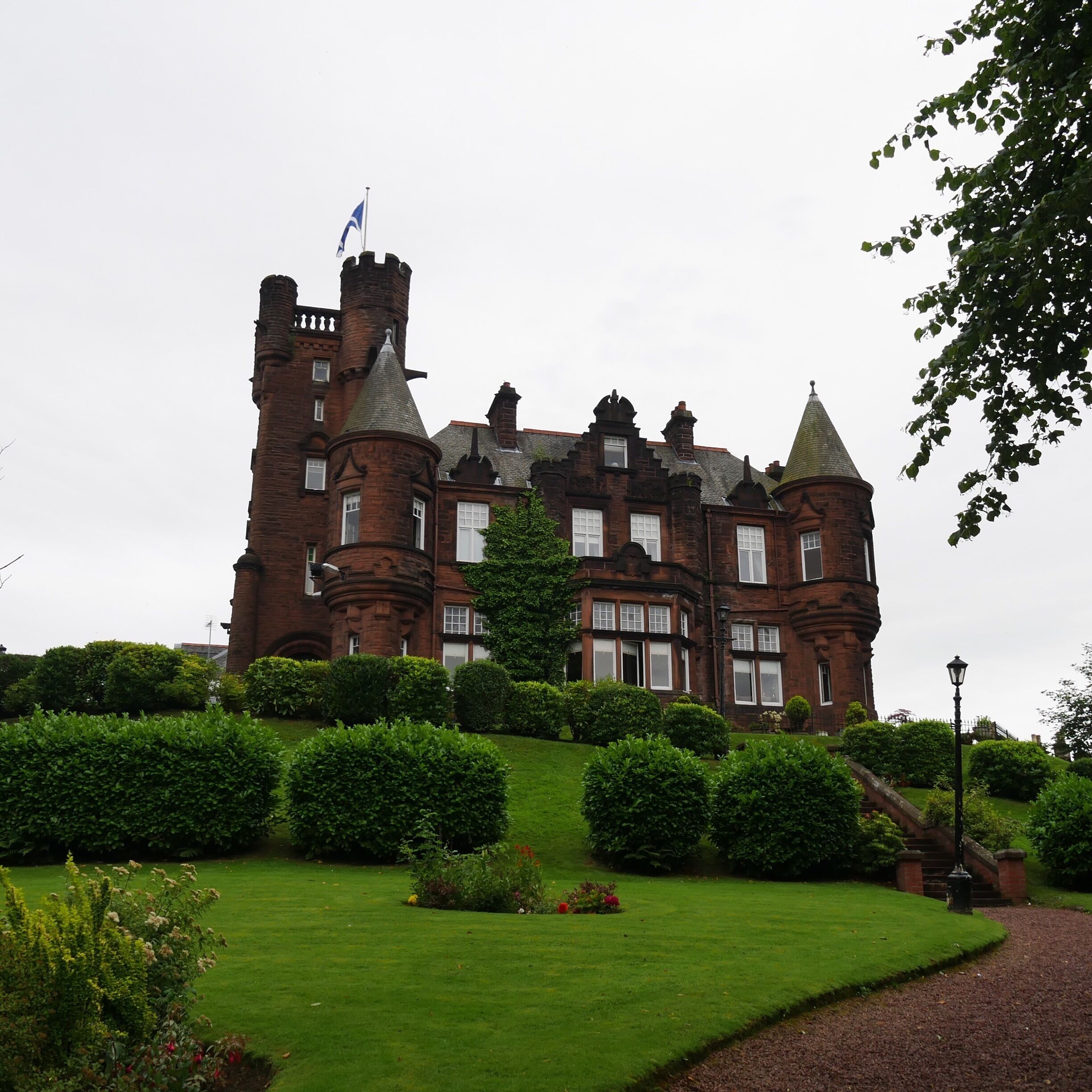 A large, historic brick castle with multiple towers and a flag on top.