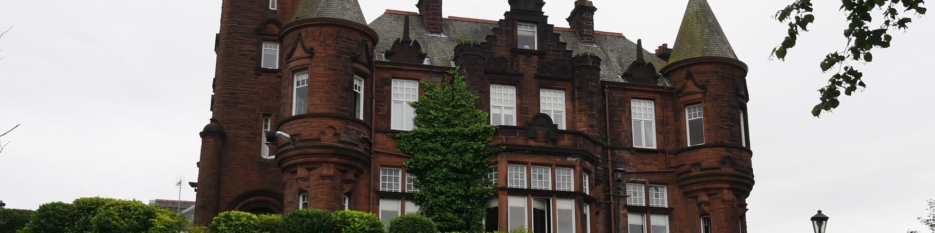 A large, historic brick castle with multiple towers and a flag on top.