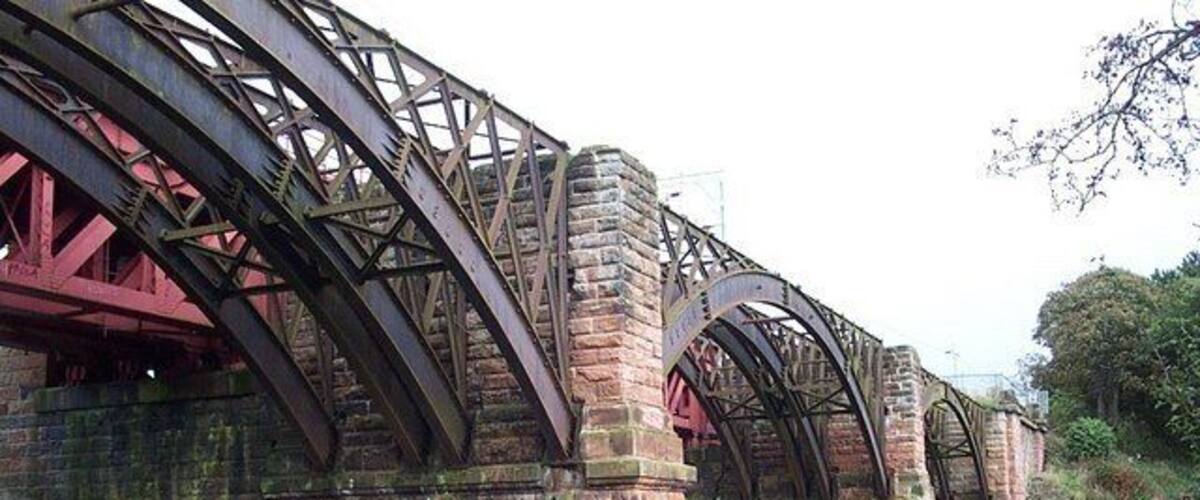 A historic brick bridge with metal trusses over a river.