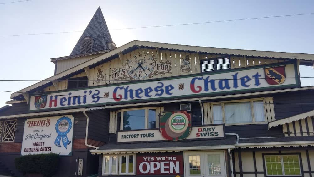 Un bâtiment sur lequel on peut lire une enseigne indiquant « Heini's Cheese Chalet » et « Oui, nous sommes ouverts », ce qui signifie que l’établissement est ouvert.