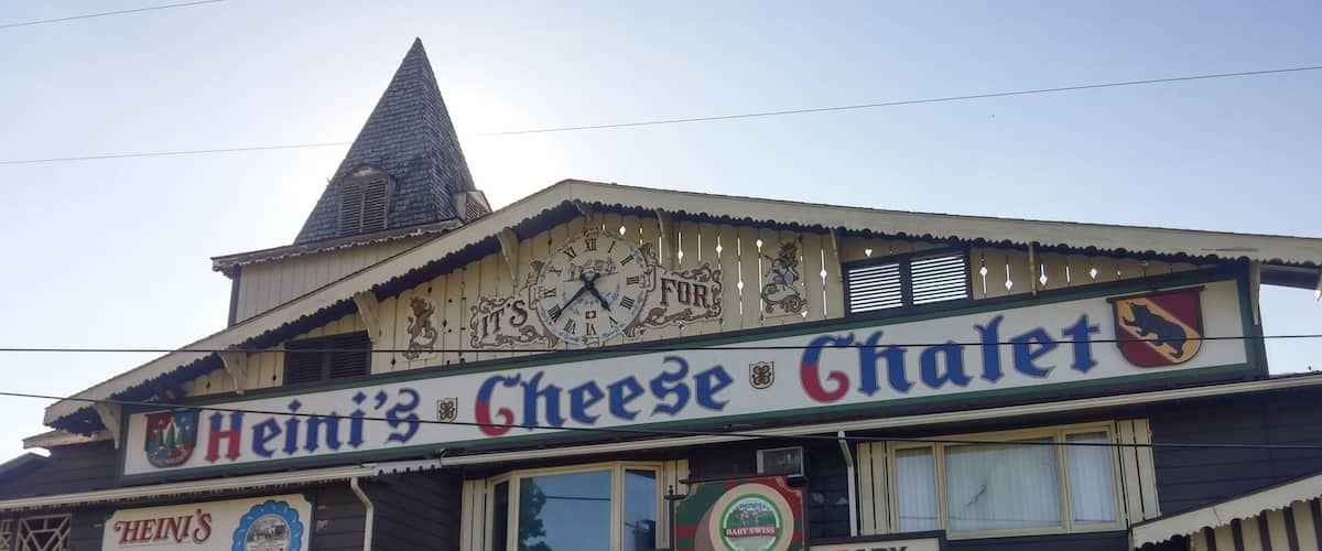 A building with a sign that reads "Heini's Cheese Chalet" and "Yes we're open" indicating the business is open.