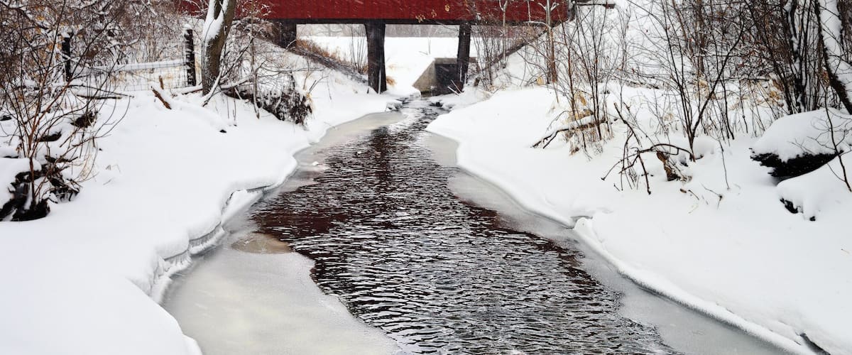 A short distance out of the small city of Milton, WI is a neat old wood covered bridge. It provides a little used road over a small meandering stream. On this Winter day we received over a foot of snow. The white flakes and the red bridge created one of my favorite Americana photos. The tree lined snowy path provides a surreal and wintery feel.