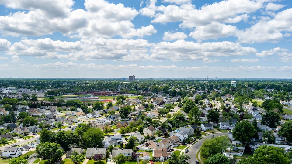 A suburban neighborhood with houses, streets, and a distant building.