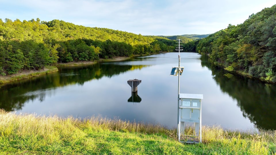 A calm river with a water tower and a control box on the bank.
