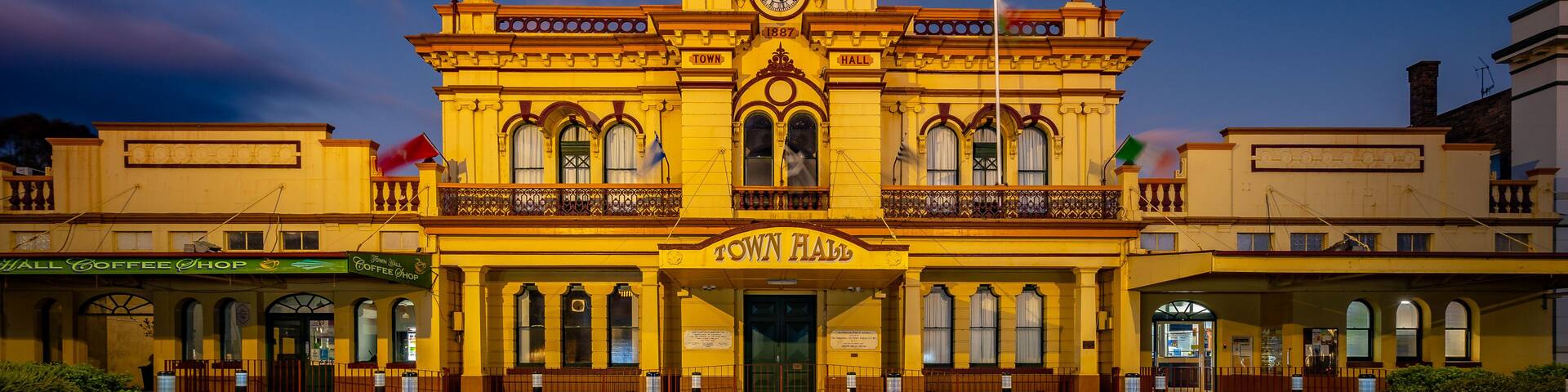 A historic town hall with a clock tower, surrounded by cobblestone streets and flagpoles.