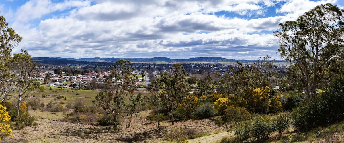 A town nestled in a valley with surrounding hills and a cloudy sky.
