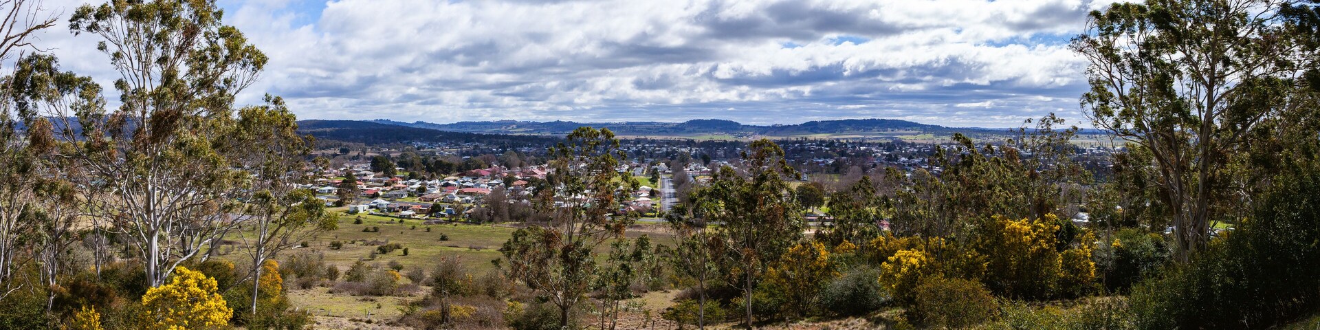 A town nestled in a valley with surrounding hills and a cloudy sky.