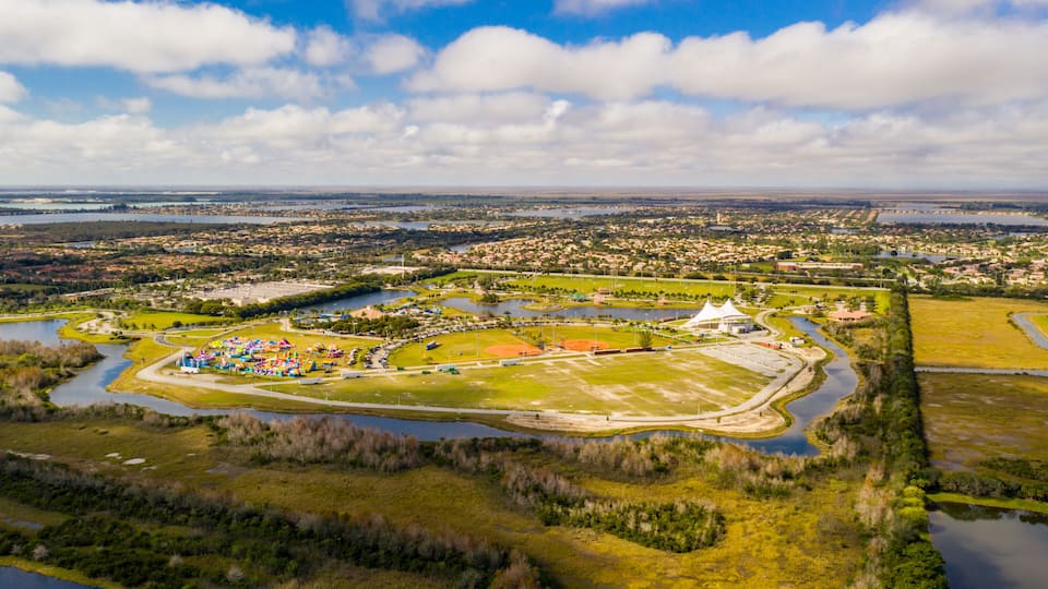 An aerial view of a park with a baseball field, water bodies, and surrounding residential areas.