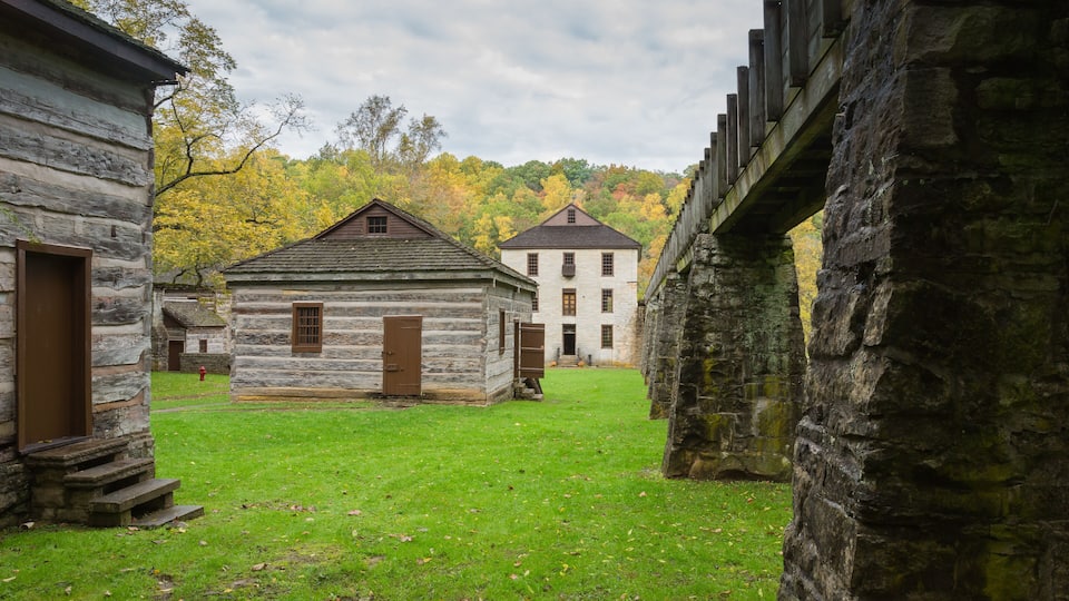 A historic building complex with stone walls and a central white building with a gabled roof.