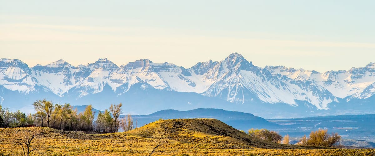 A mountain range with snow-capped peaks and a valley with sparse vegetation.