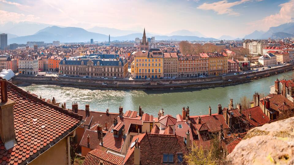 Scenic panoramic aerial view of the banks of the Isere river, bridge, and Old Town with French Alps on the background, Grenoble, France