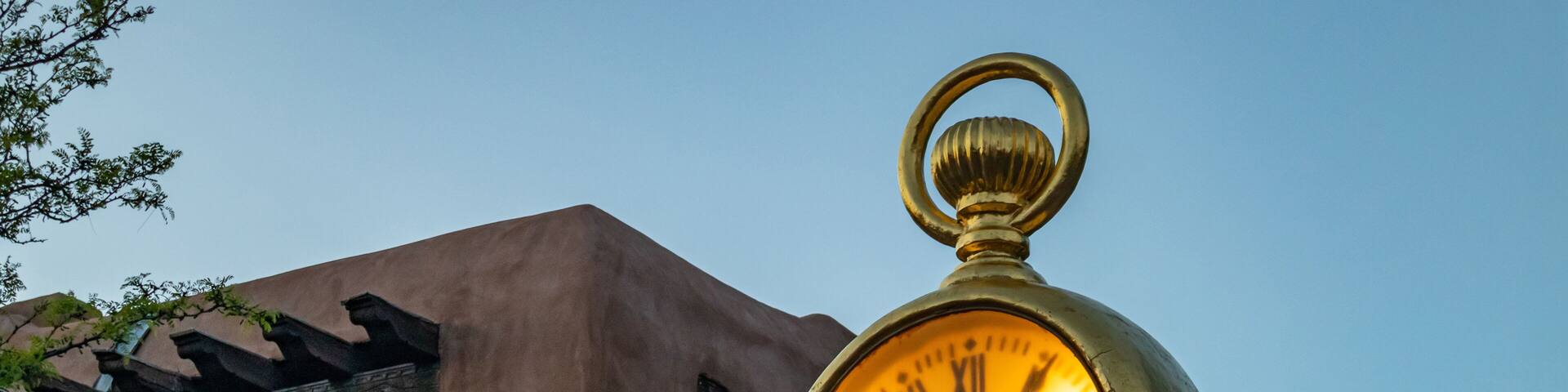 Gold post clock outdoor in Santa Fe plaza, traditional Rchitecture and blue sky at sunset background, New Mexico, US.